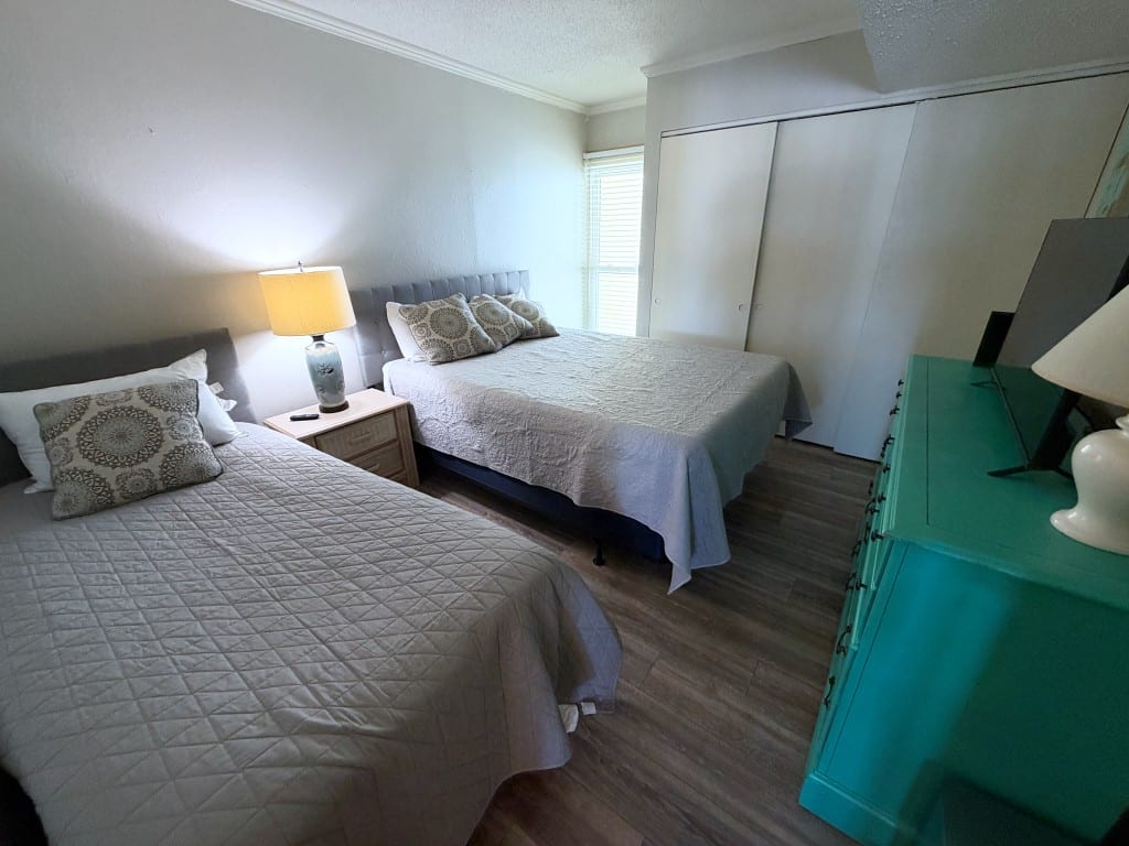 Second bedroom with a queen bed, a twin bed, and a turquoise dresser with a television