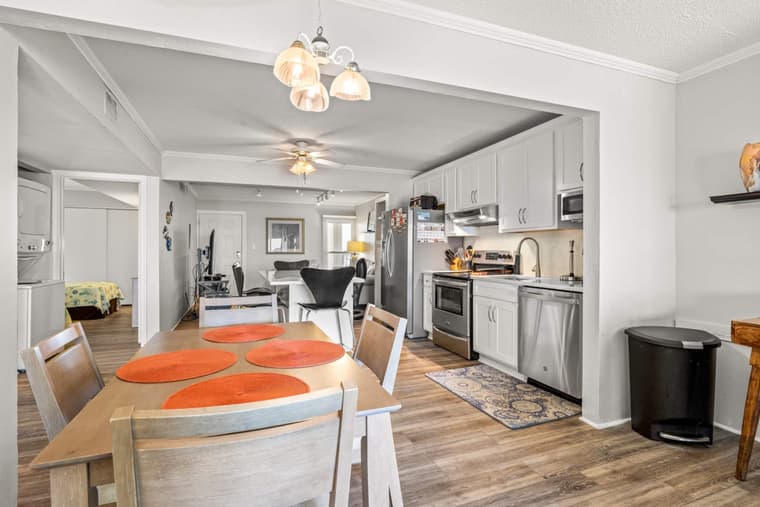 Dining table and chairs beside the kitchen, with the living room and balcony doors beyond.