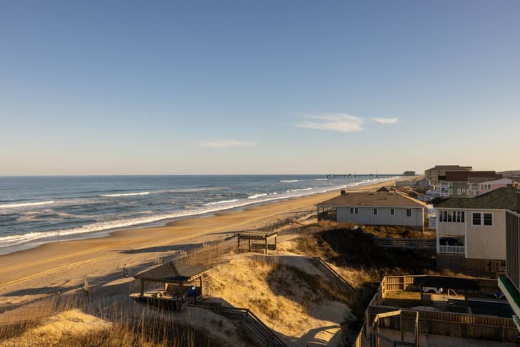 View from the top floor along the dune line, with the beach, the ocean, and neighboring houses.