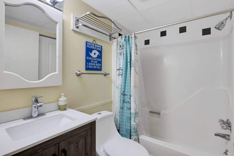 Second full bathroom with a vanity, mirror, and a tub with shower.
