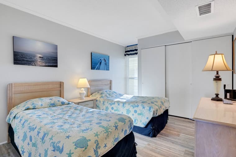 Second bedroom with two twin beds in coastal bedding, a dresser, and a closet.